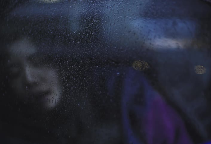 Sleeping woman seen through a car window with water droplets