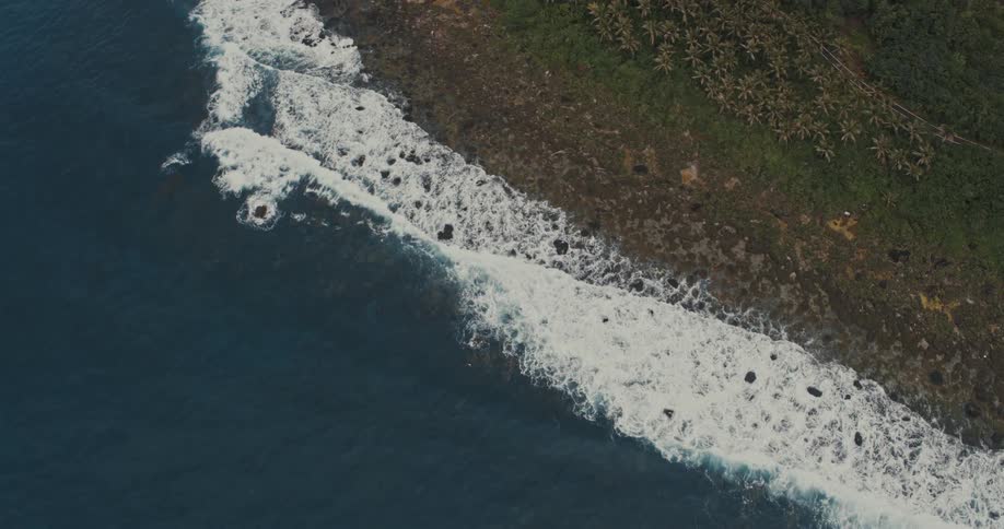 Sea waves breaking on a coast creating white foam on the surface of the water
