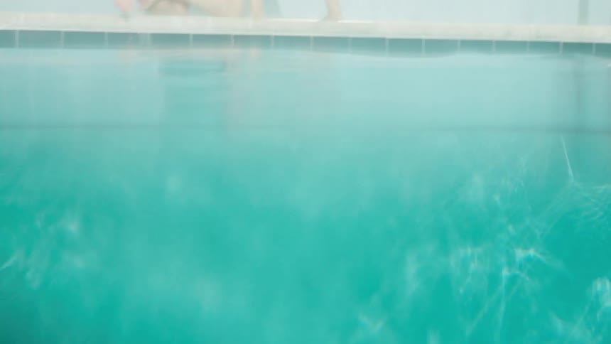 A man climbs up out of the pool