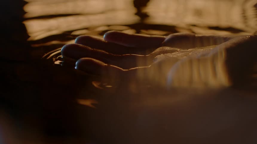 A hand is moving in the dark water