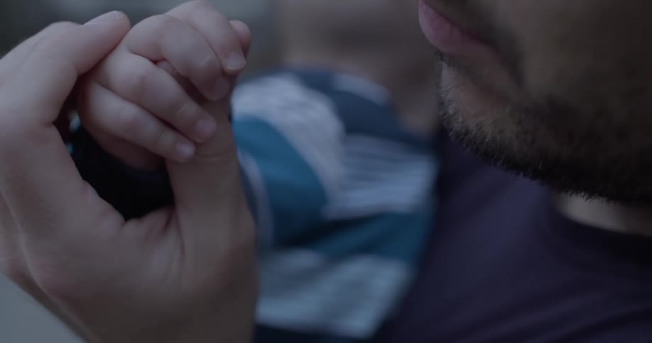 Father holding young son's tiny hand and fingers