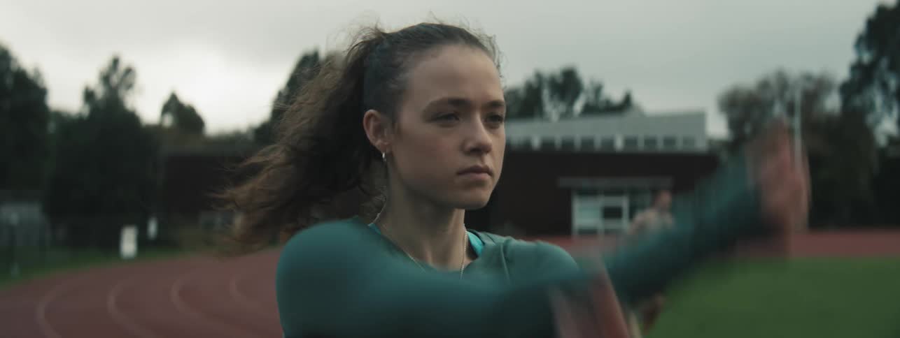 Close up of a young woman swinging her arms while exercising outdoors on a track during the day