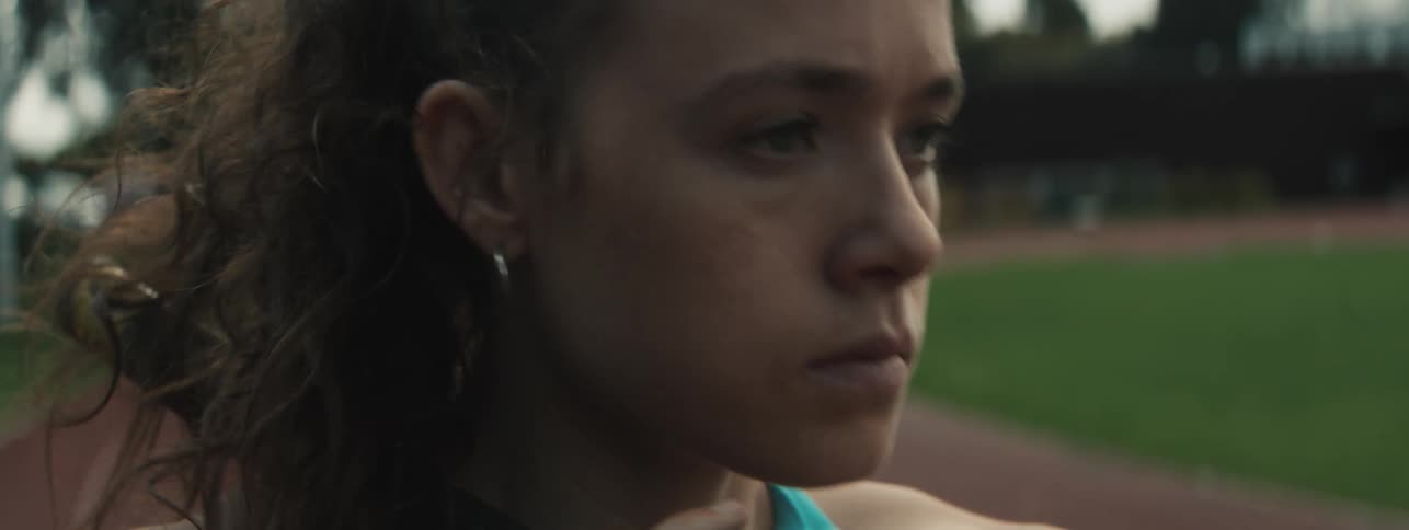 A young woman pauses in focus preparing to run on the track
