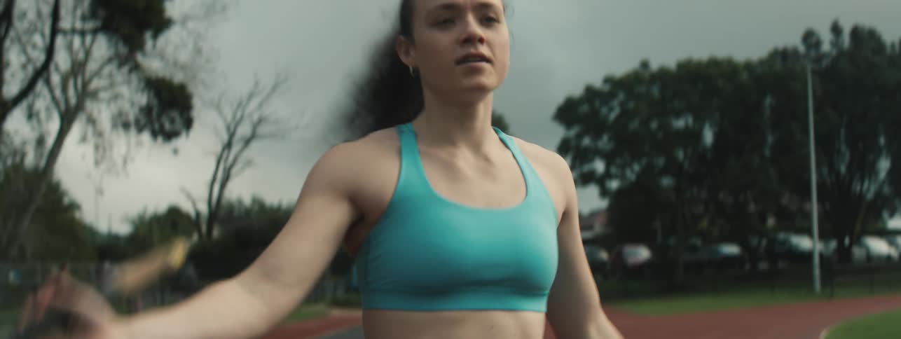A female athlete sprints on a track holding a pole for pole vaulting