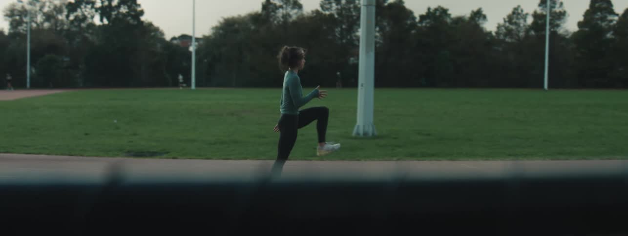 A girl warms up with high knee exercises around a track