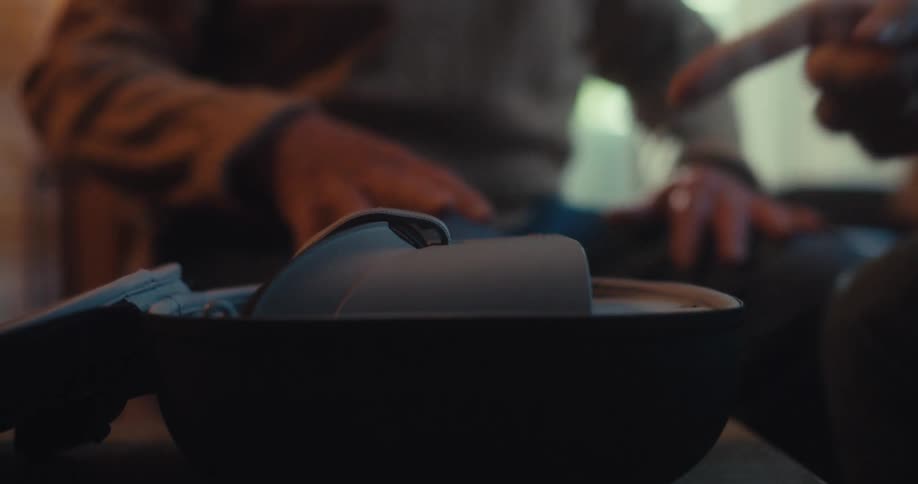 Man shows a virtual reality headset to an elderly man while sitting in the living room