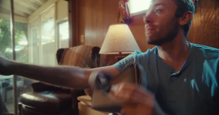 Elderly man sitting at home smiles while a younger man discusses a virtual headset with him