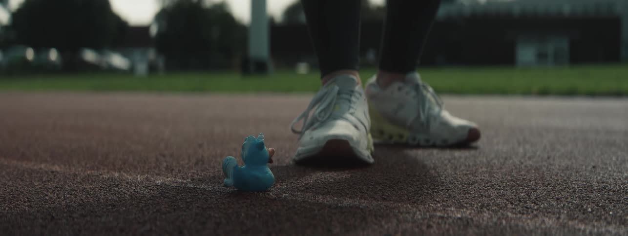 Person adjusting a small blue toy on a running track