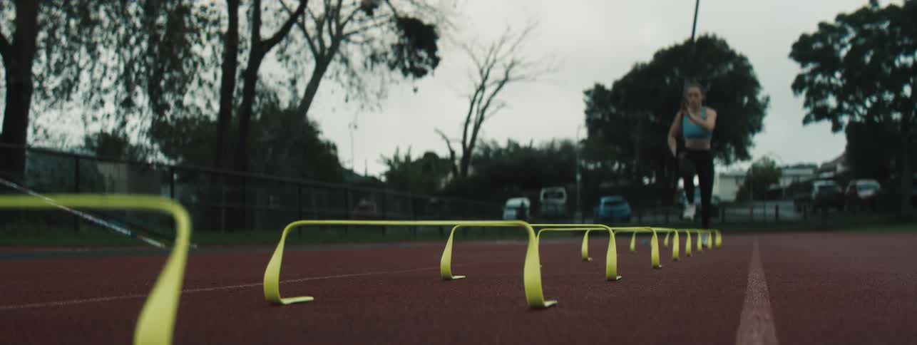 Female athlete runs with a vaulting pole while training on a summer day