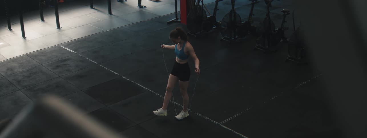 Young woman jumps rope in an empty space in the gym during the day