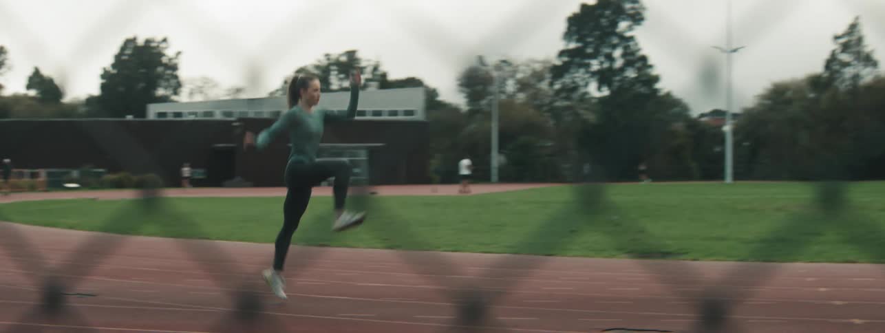 A woman runs down a running track while intermittently hopping