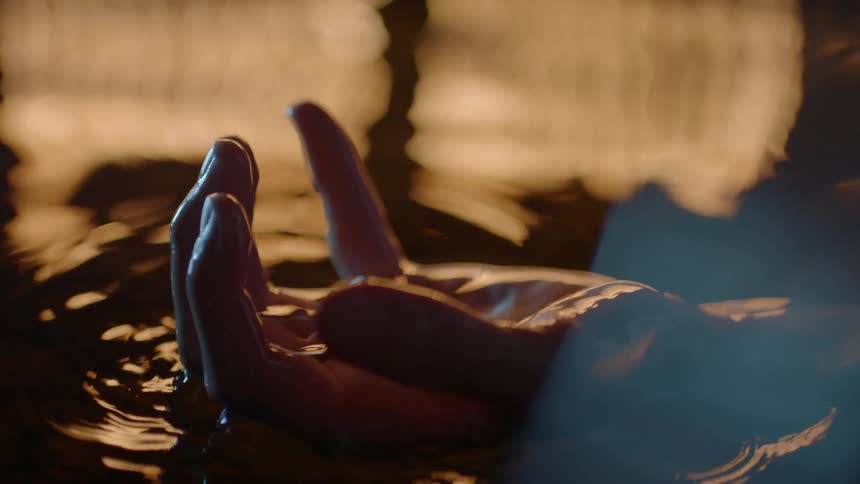 A person's hand reaches out of the water