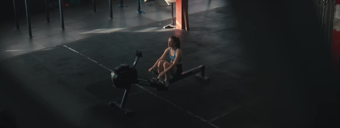 Woman exercises on the rowing machine in the gym during the day