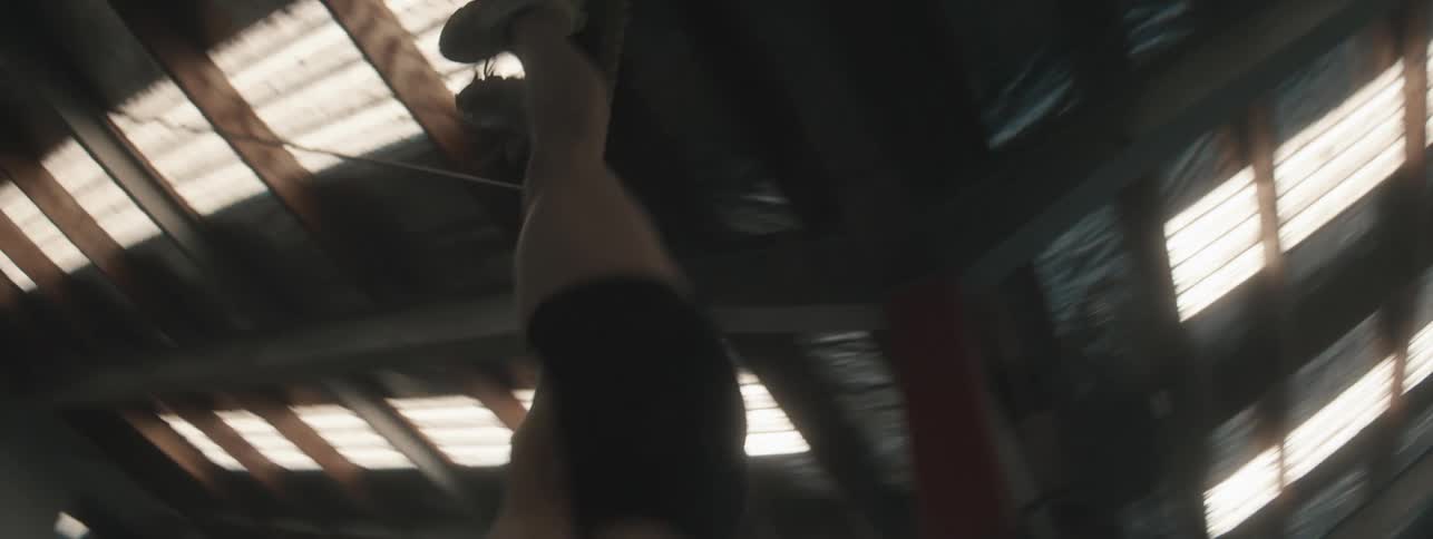 Woman briefly flips herself upside down on a rope in a large gym