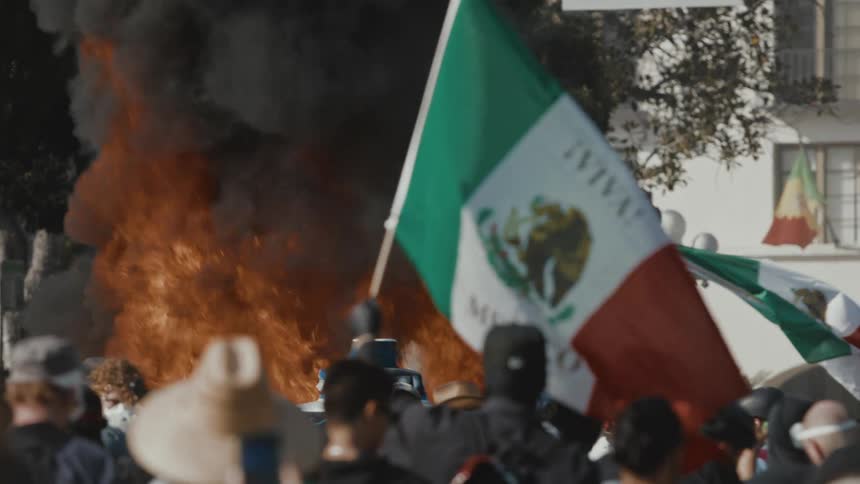Protesters stand in front of a large flame