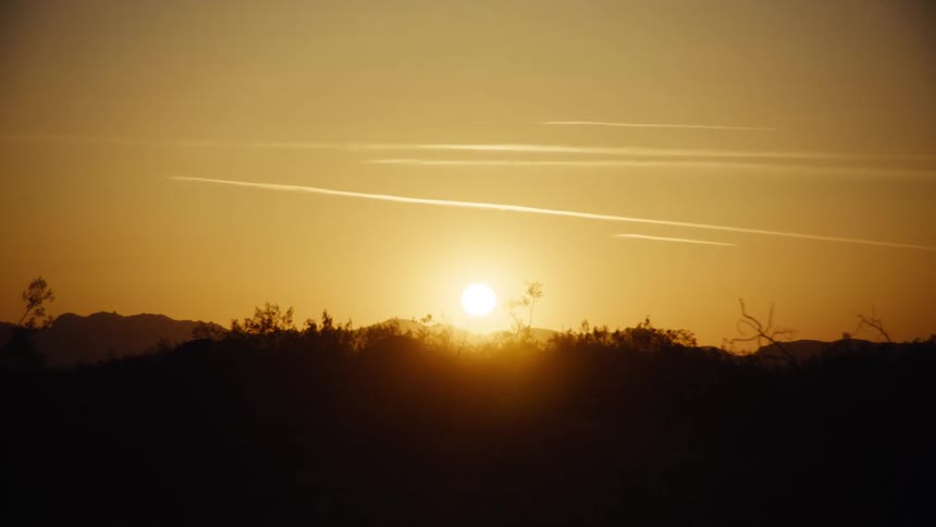 Bright yellow sun setting on the horizon over the hills