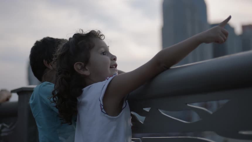 Children laugh and point leaning on a railing