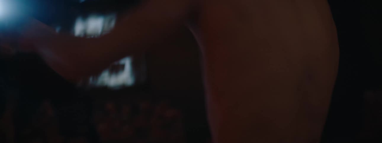 Two people are boxing in a dimly lit environment
