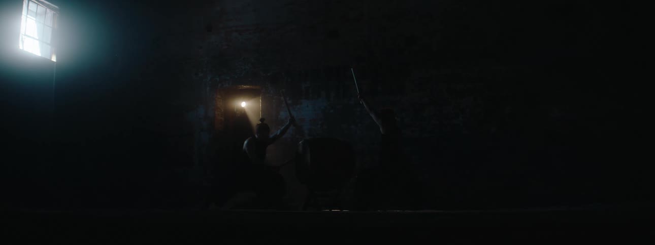 Taiko drummers perform in a dark area lit by a moving spotlight