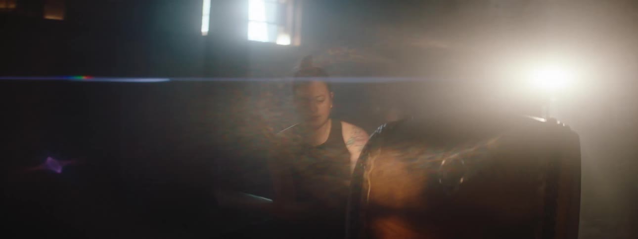 Taiko drummers perform in a dim area lit by a spotlight