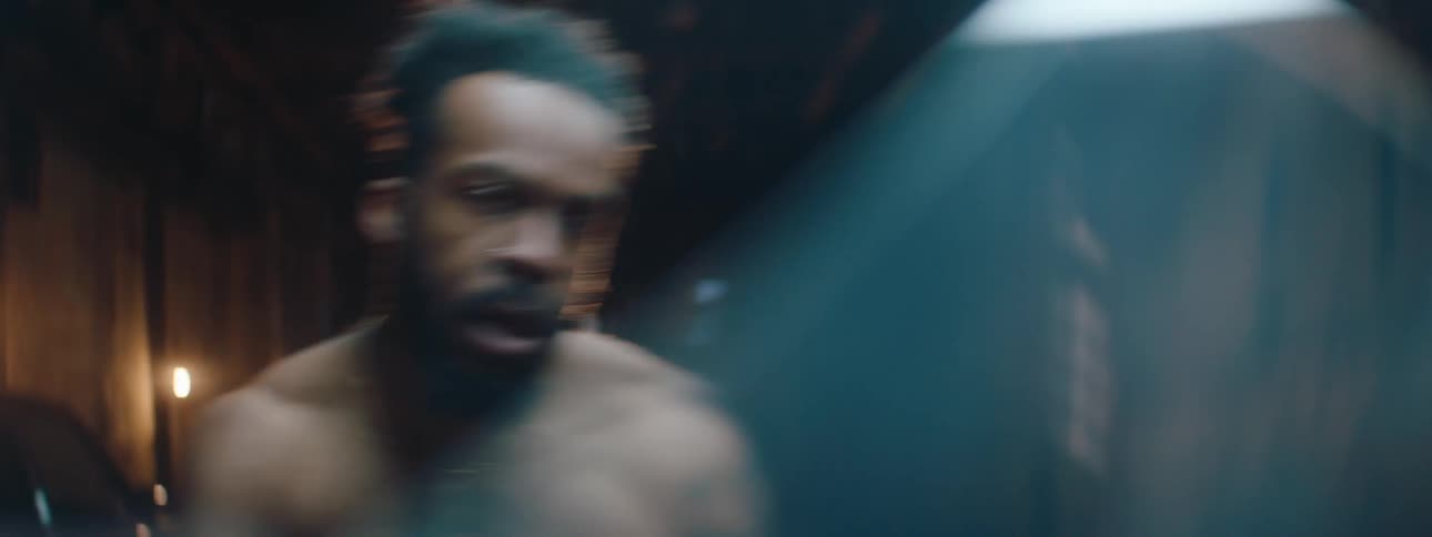 The man is punching and kicking in front of a spotlight