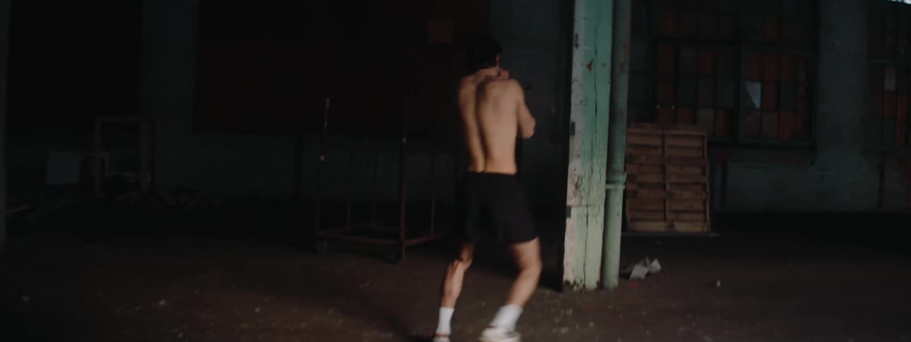 Young man practices and trains martial arts in the middle of a hall inside an old building