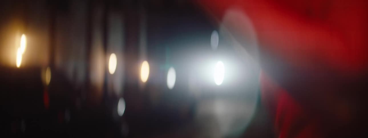 A shirtless man is practicing boxing by throwing punches to his front and he is under a red light