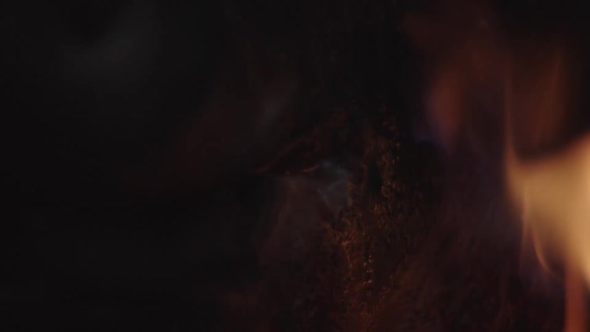 A charred pigs head with bright flames burning beside it