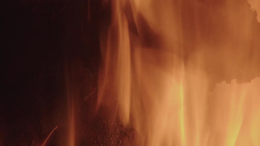 A glowing flame of fire burning something dark in a night