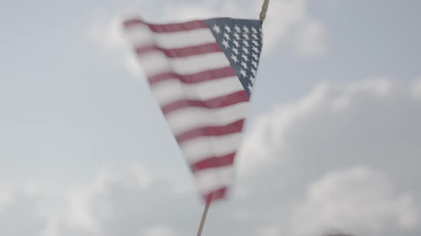Woman picks up an american flag and holds it above her head