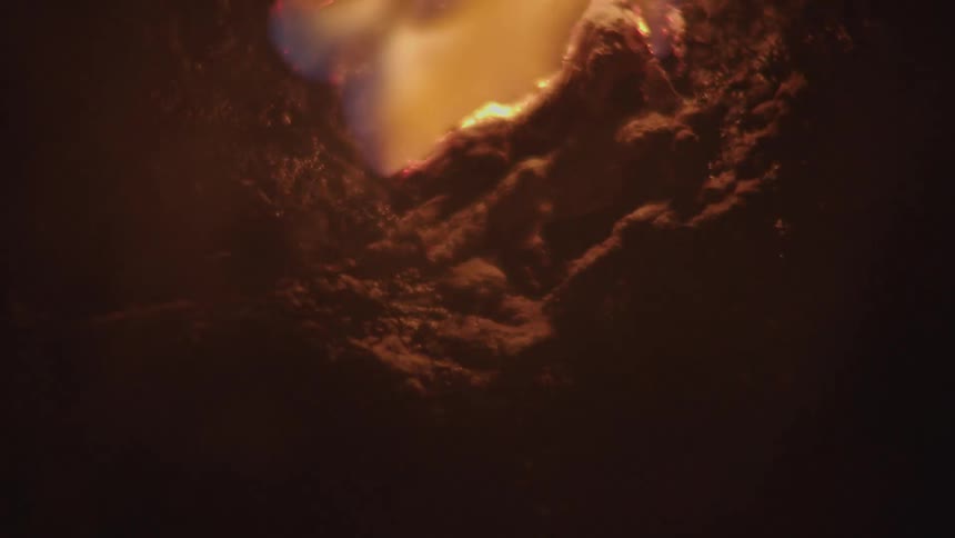Close up of flames engulfing a dark textured charred material