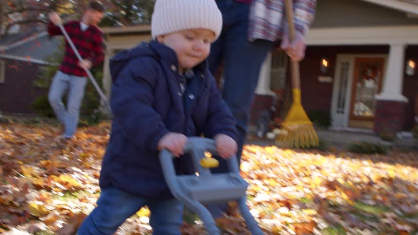Little boy in a cap walking in a yard with dry leaves with a toy
