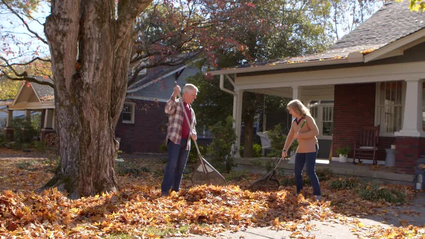 A man and woman are raking in the yard