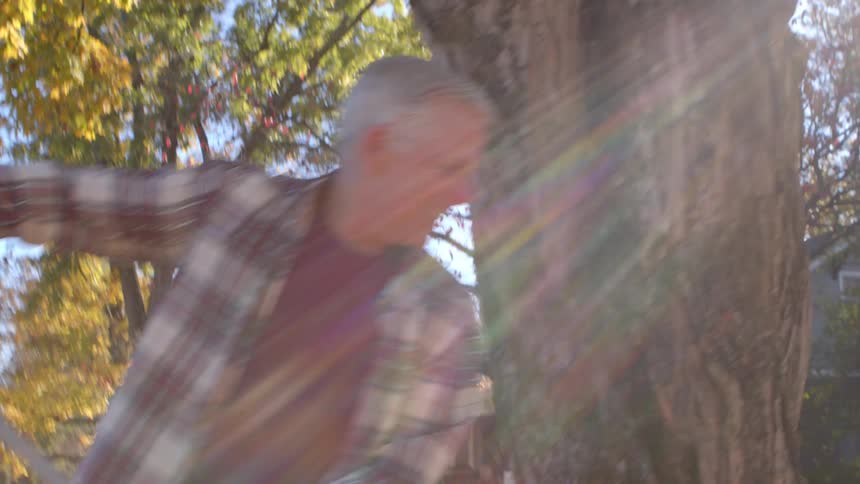 Cheerful man cleaning a yard of leaves