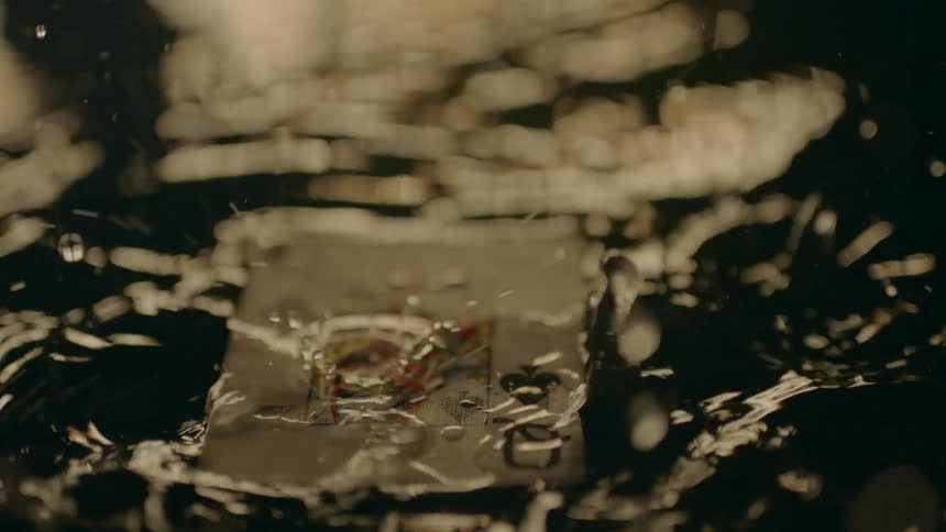 A card floats in the water as drops pour over it