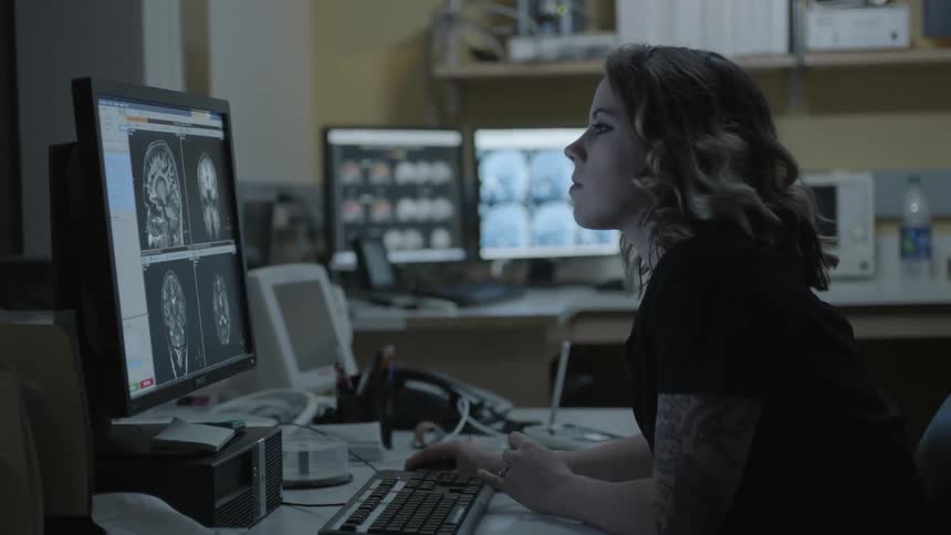 A woman looks at brain imagery on a computer monitor