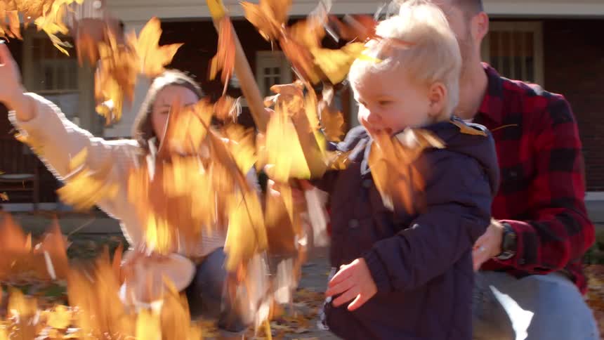 A family have fun in the yard throwing leaves