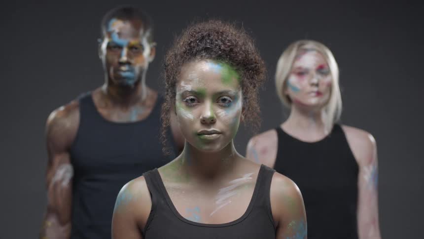 Three people stand looking forward with paint on their faces
