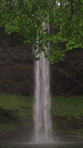Long narrow waterfall flowing into a pool of water in the canyon