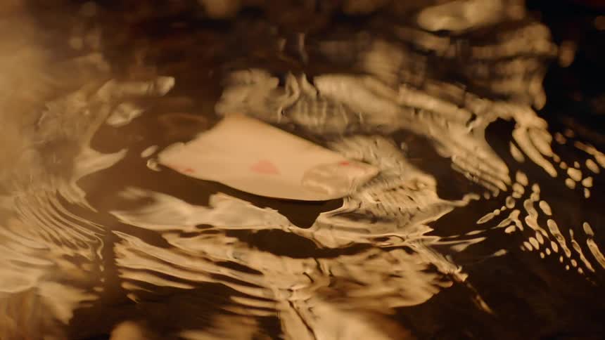 A playing card falls into a puddle of water