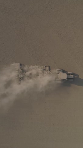 A tractor drives through a dusty field