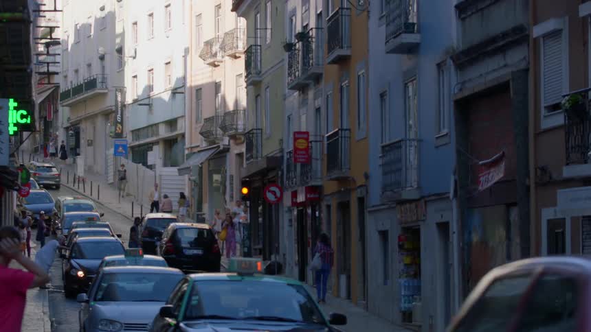 Traffic and pedestrians move along a narrow city street