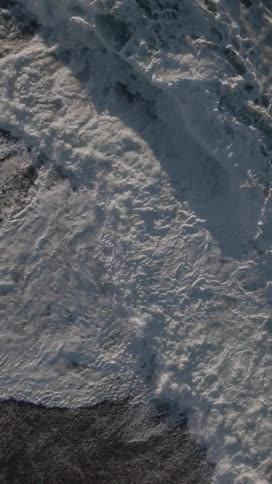 Small foamy sea waves crash onto a sandy beach shore