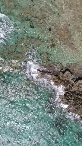 An aerial view of some small waves breaking on the shore on some rocks