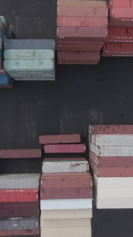 An aerial shot captures numerous colorful shipping containers neatly stacked in an industrial port or shipping yard