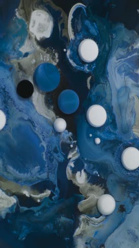 A macro abstract view features various sizes of white blue and black spheres suspended in swirling patterns of blue gray and white fluid