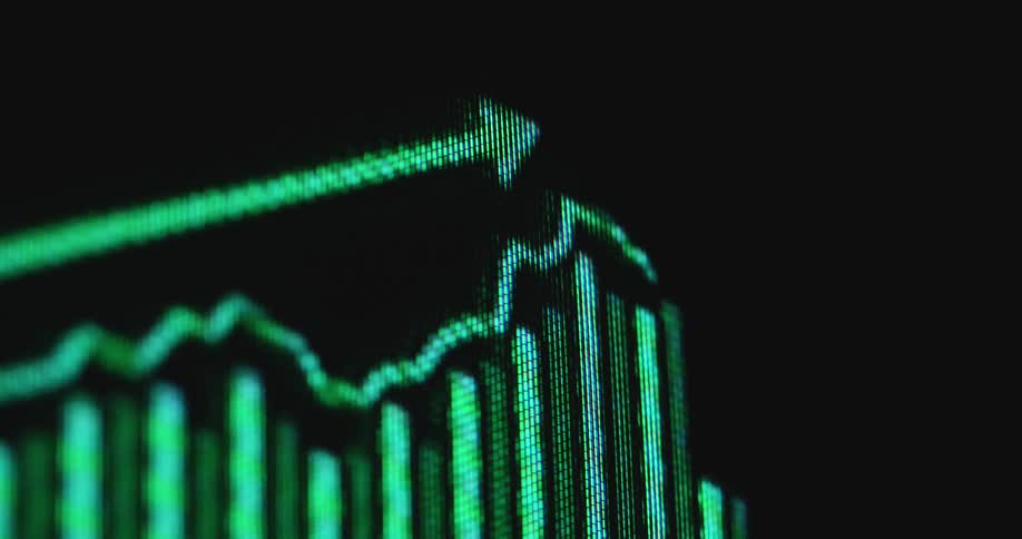 Retro computer monitor or screen displaying a neon green growing graph of a vintage broker or trading software enabling users to buy and sell stocks online in order to make profit and earn money and invest for their future