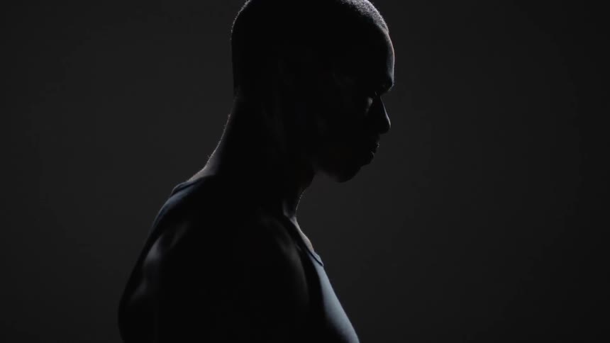A man stands still in profile