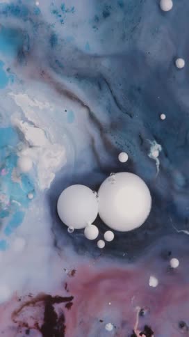 White bubbles of various sizes floating serenely in a slowly swirling cosmic like mixture of blue purple and pink liquids