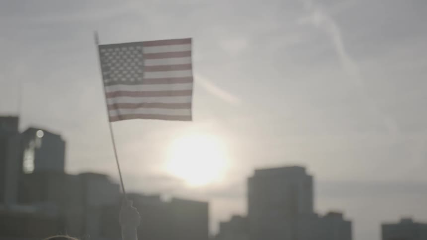 A woman holds her arm up and waves an american flag